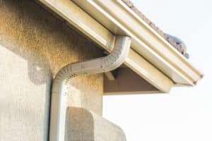close up of gutter and downspout on a light tan stucco home.