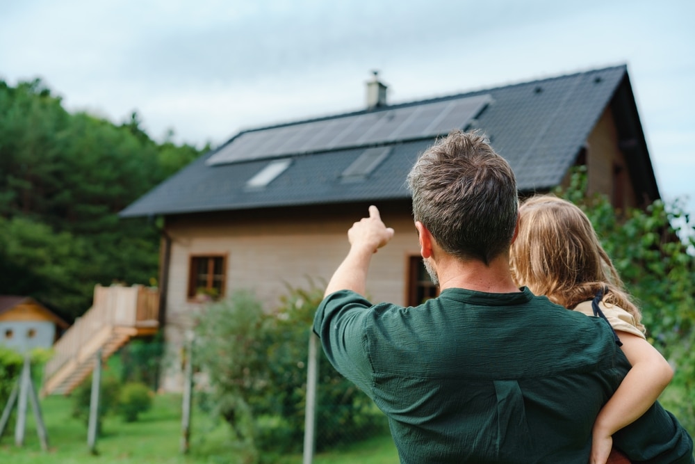 Rear view of dad holding her daughter while pointing at their newly installed roof