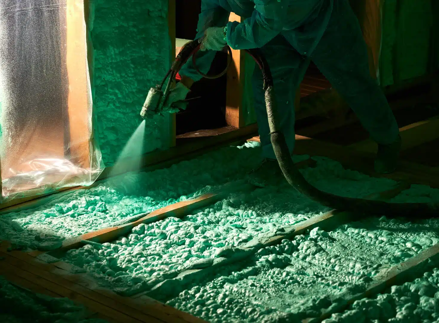 Installer applying spray foam insulation to an interior wall