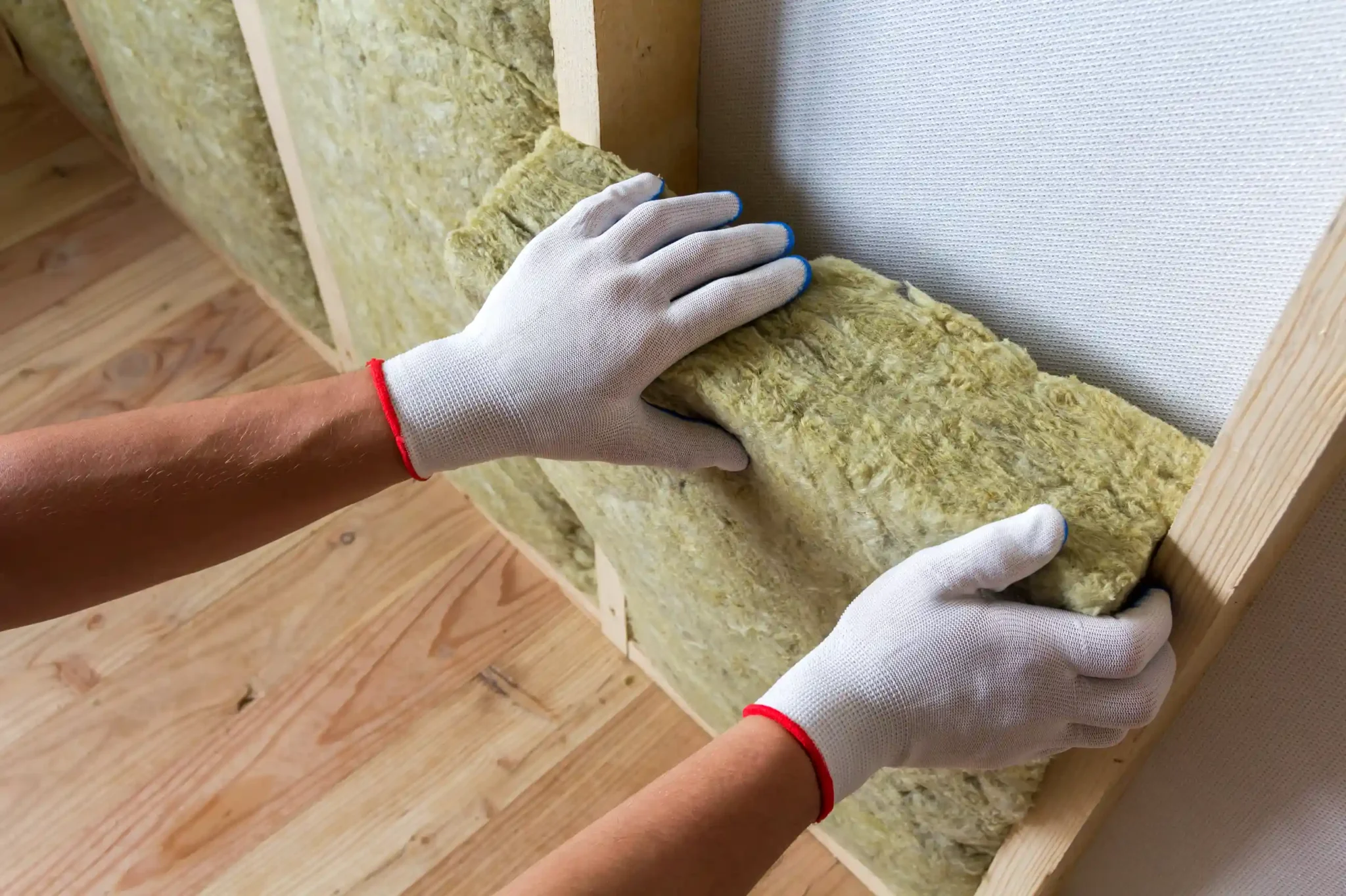 Worker placing insulation against wall
