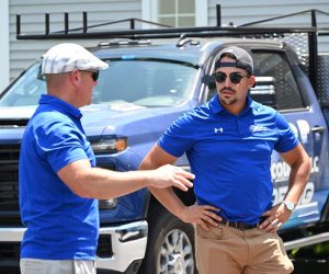 Adam Vaillancourt Roofing team members talking beside a branded company truck
